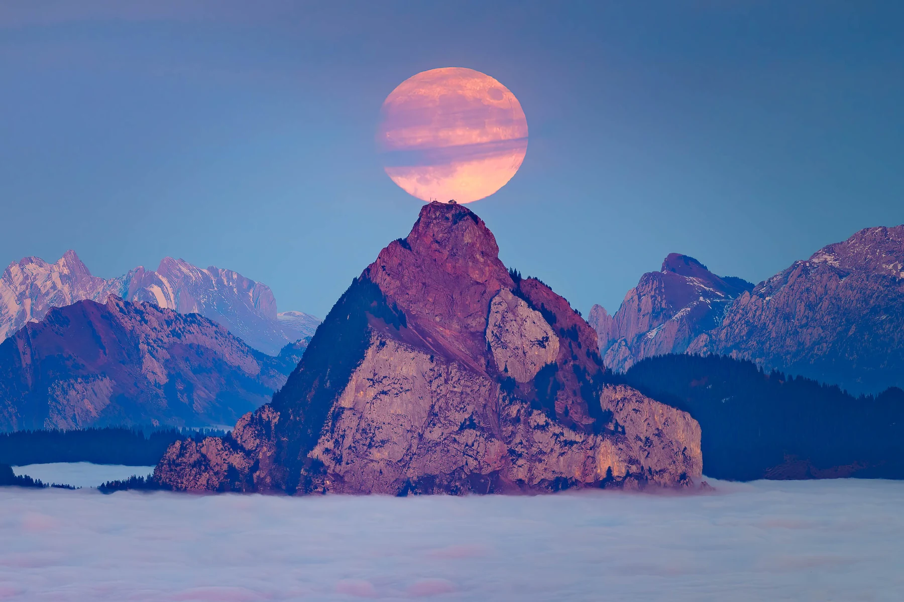 Vollmond über einem Berggipfel und Nebelmeer